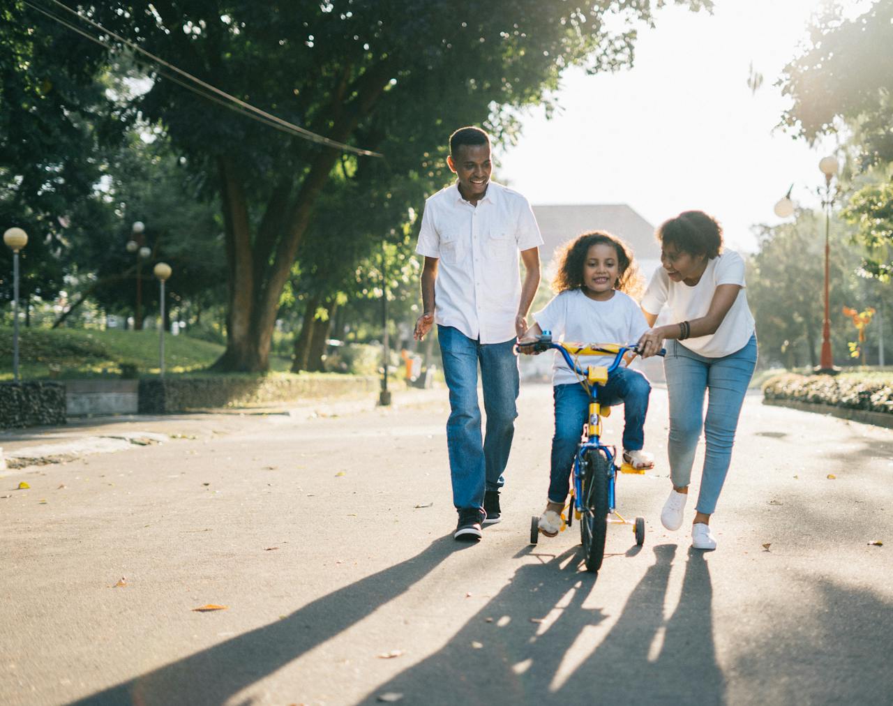 about-01 Happy family teaching their child to cycle on a sunny day outdoors.
